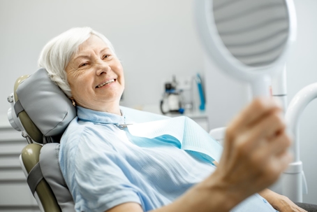 Woman smiling at a hand mirror