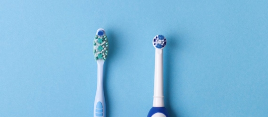 Manual toothbrush next to an electric toothbrush