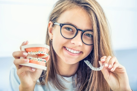 woman holding a display of teeth with braces