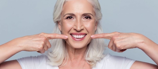 woman pointing at her white teeth